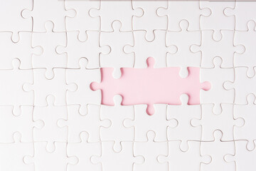 Top view flat lay of paper plain white jigsaw puzzle game texture incomplete or missing piece, studio shot on a pink background, quiz calculation concept