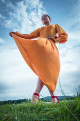 latina woman in big yellow dress holding her dress bottom view