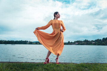 young latina woman takes her traditional dress and looks confident in front of a lake
