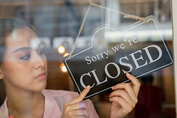 Sad asian young owner retail, coffee shop woman turning sign board to closed after finished work,...