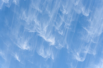 Peaceful wispy white clouds against a clean blue sky as a nature background
