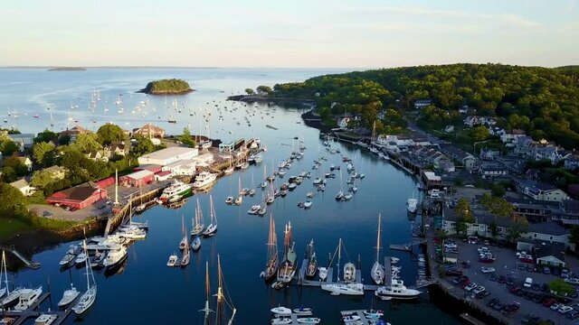 A beautiful golden hour aerial drone shot tour from the head of Camden Harbor to the entrance showing schooners, sailboats, a boatyard, and one of Maine&rsquo;s most picturesque tourist towns.