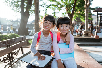 smiling two young little girl student holding book