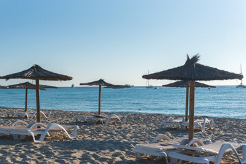 Straw umbrellas and sunbeds on the beach of Illetes in Formentera, Spain.