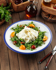 Burrata cheese arugula salad on a rustic wooden background