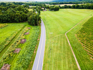 Aerial top view of a rural road along fields and farms
