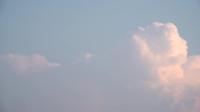 A time lapse of cumulus nimbus clouds building rapidly on a blue sky background in the early evening dusk.