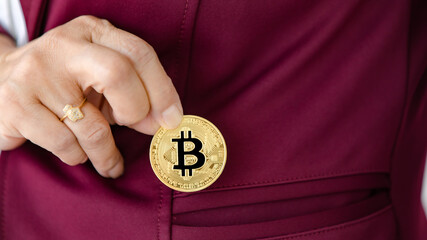 Woman's hand holding crypto coin and putting into pocket. Concept of investment in digital assets...