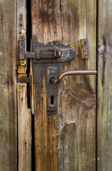 details of old weathered beautiful textured wooden barn door with iron, rusty latch and door handle