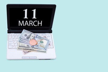 Laptop with the date of 11 march and cryptocurrency Bitcoin, dollars on a blue background. Buy or sell cryptocurrency. Stock market concept.
