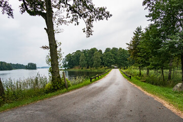 Fototapeta na wymiar Hofsnas, Sweden A rural road by a lake and a small bridge.
