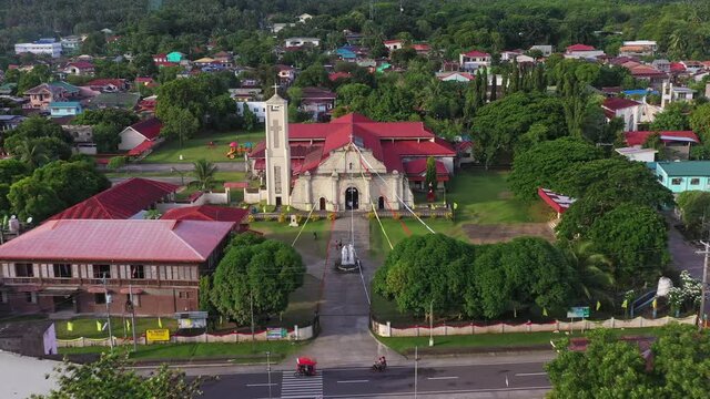 Cabalian Historical Church In The Coastline Of Southern Leyte With Crane Vessel At The Harbour Revealed. aerial drone pullback