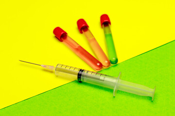 Medical syringe with needle and sample tes tubes on colorful background
