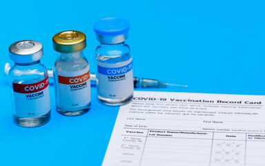 Covid-19 vaccine doses bottle, vaccination record card, and medical syringe prepared at clinic to inject volunteer as measure for social immunity against outbreak.