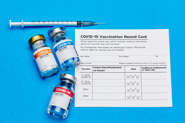Covid-19 vaccine doses bottle, vaccination record card, and medical syringe prepared at clinic to...