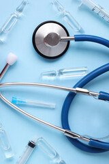 Medical layout on blue background, flat lay. Blue stethoscope or phonendoscope with test tubes, bubbles or ampoules, place for text