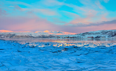 Panoramic view at fjord with coast of the Norwegian Sea in the background snowy mountains Arctic Circle at sunset - As a result of melting snow, freezing of the water mixed with the sea -Norway