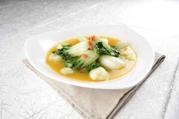 stir fried small cabbage with Chinese herbal in yellow chicken stock soup in white background asian halal vegan menu