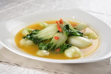stir fried small cabbage with Chinese herbal in yellow chicken stock soup in white background asian halal vegan menu