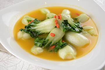 stir fried small cabbage with Chinese herbal in yellow chicken stock soup in white background asian halal vegan menu