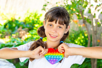 Funny teenage girl playing with rainbow antistress on the street. The push bubble fidget sensory toy is a stress relief toy. Portrait. Close-up.