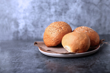 three buns of different kinds on wooden plate isolated on gray background