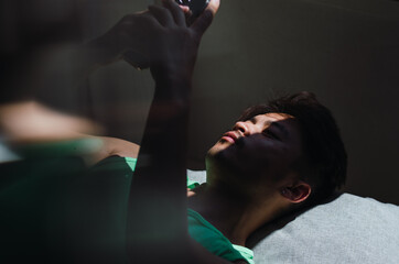 Portrait of pensive young handsome Chinese man lying on floor and looking away