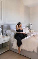 Pregnant Carribean Indigenous woman drinking water in and relaxing in bed
