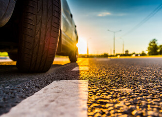 Sunset in the country, the empty highway. Wide angle view of the level of a parked car wheels