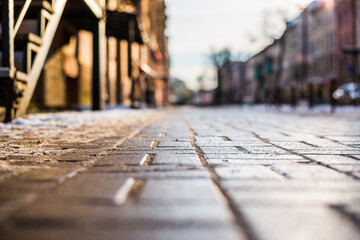 Bright winter sun in a big city, empty street with snow. Close up view from the sidewalk level