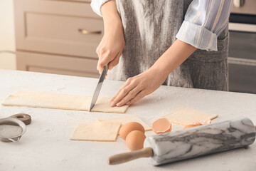 Woman cutting dough on kitchen table