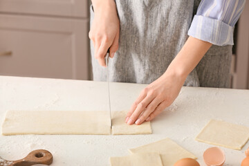 Woman cutting dough on kitchen table
