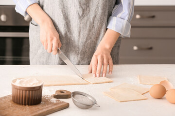 Obraz na płótnie Canvas Woman cutting dough on kitchen table
