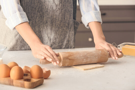 Woman rolling out dough on kitchen table