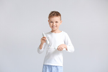 Little boy brushing teeth on grey background