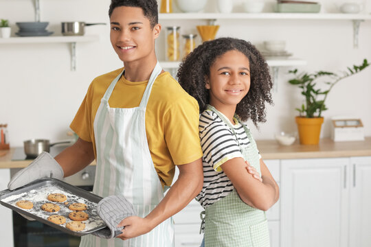 African-American brother and sister with tasty homemade cookies in kitchen