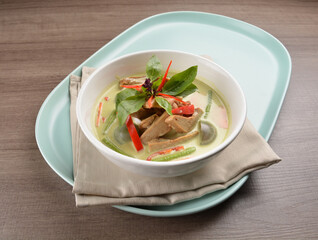 thai spicy chili green curry hot soup with vegetarian meat in bowl blue plate on wood background asian halal vegan menu