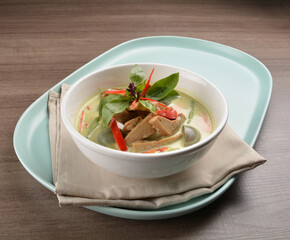 thai spicy chili green curry hot soup with vegetarian meat in bowl blue plate on wood background asian halal vegan menu