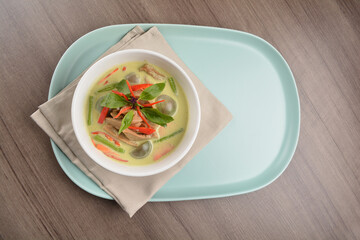 thai spicy chili green curry hot soup with vegetarian meat in bowl blue plate on wood background asian halal vegan menu