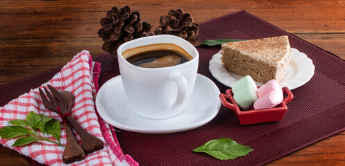 A glass cup of black tea with cake on a dark greyish marble background