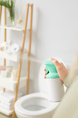 Woman spraying air freshener in bathroom