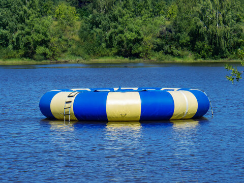 Large inflatable round blue trampoline on a pond