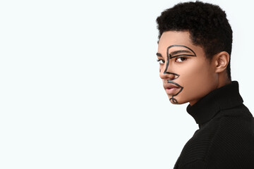 Obraz premium Young African-American guy with paint on face against light background