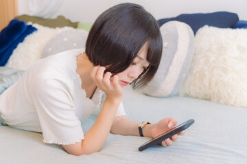 ベッドでスマホを見る女性