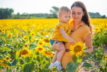 Happy mother and her little daughter in the sunflower field