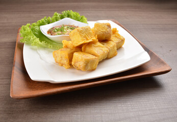 deep fried bean curd tofu with Thai spicy chilli sauce on wood background asian halal vegan menu