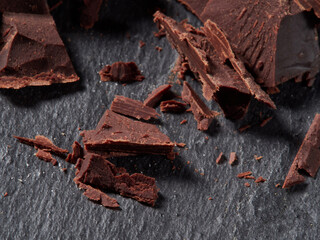 Broken pieces of chocolate and cocoa powder on a black background