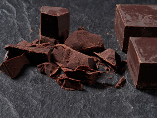 Broken pieces of chocolate and cocoa powder on a black background
