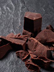 Broken pieces of chocolate and cocoa powder on a black background