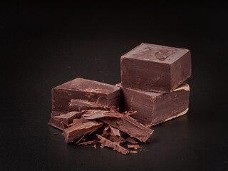 Broken pieces of chocolate and cocoa powder on a black background
